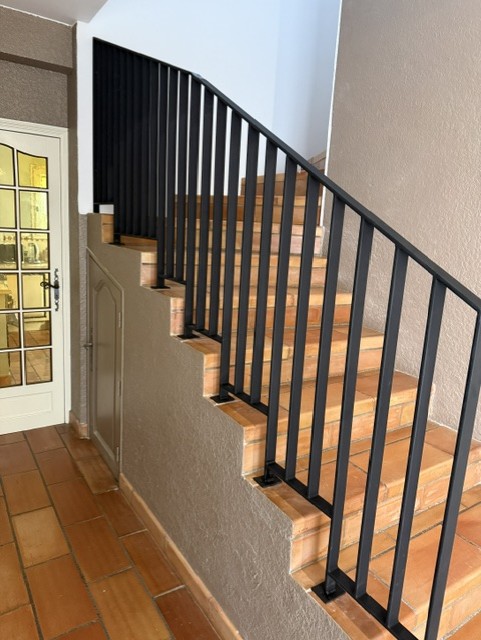 Rampe métallique noire suivant la montée d’un escalier